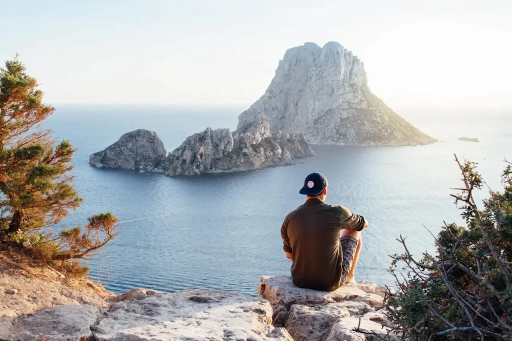 Man Sitting On A Rock Looking At Ocean